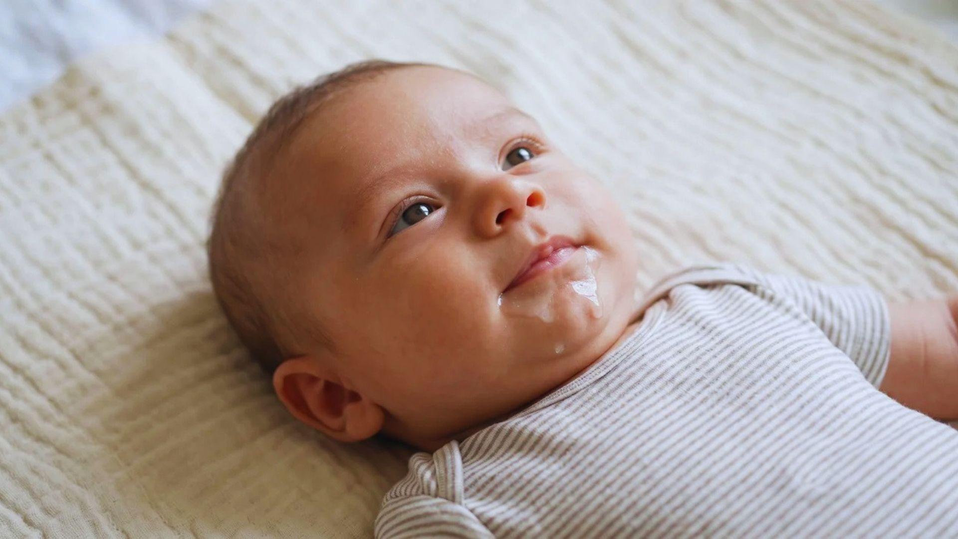 Young baby lying on a blanket with saliva around the mouth.