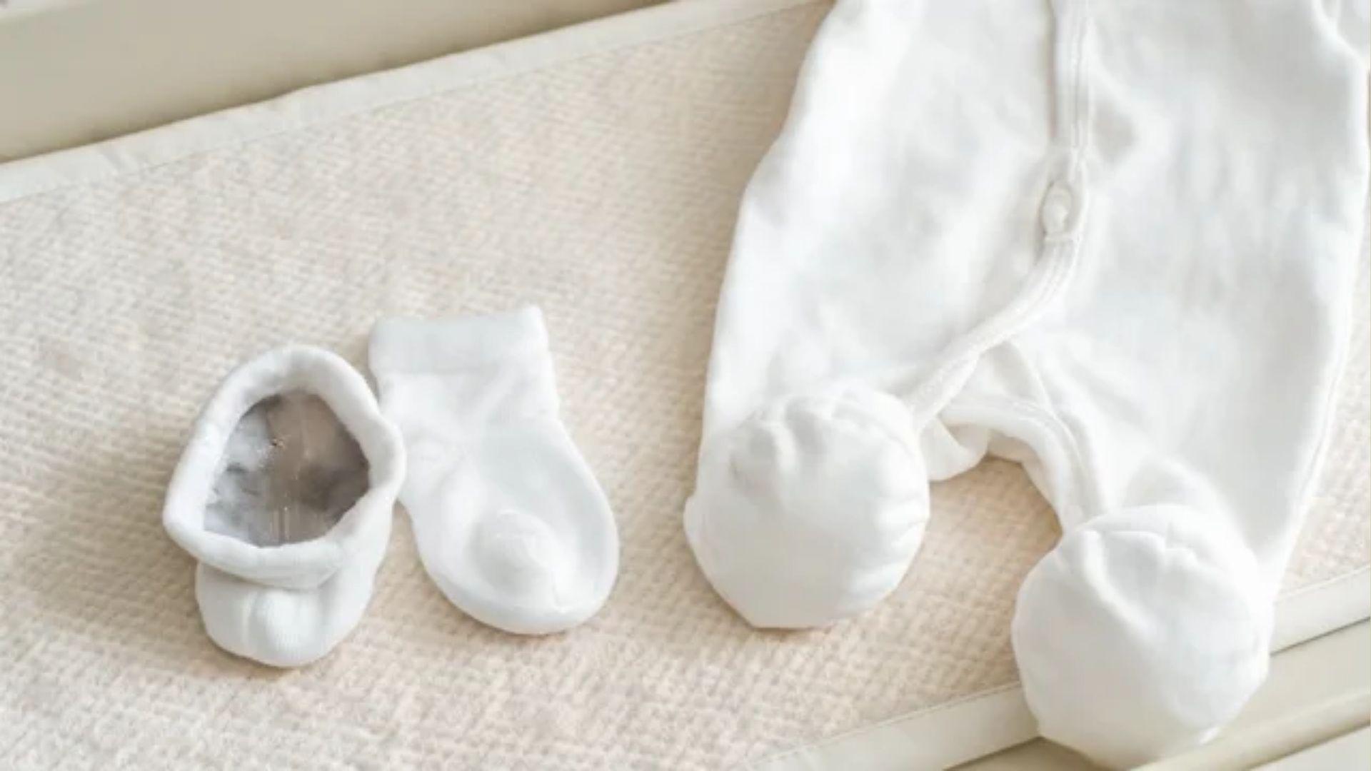 Baby socks with visible moisture beside a cotton footed sleeper