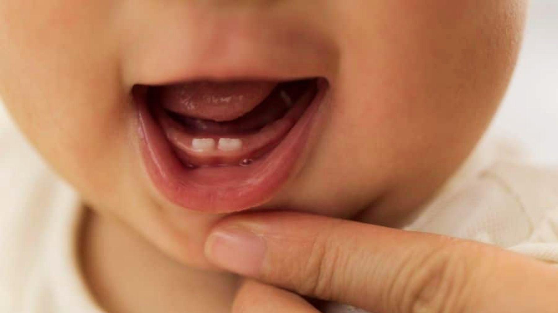 Close-up of baby smiling showing two bottom front teeth emerging.