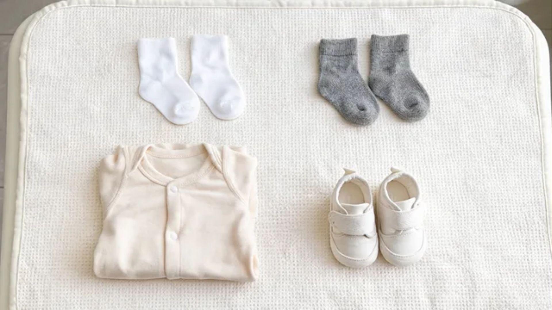 Cotton and wool baby socks beside a cotton footed sleeper and lightweight baby shoes