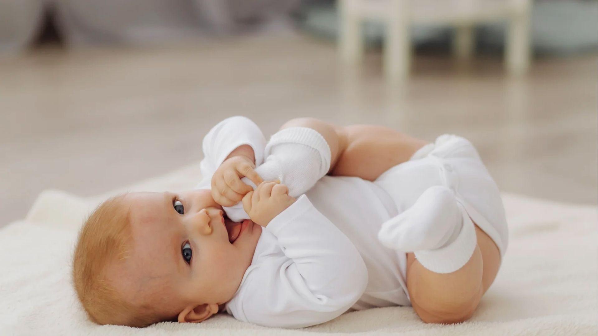 Awake baby on a play mat chewing a solid rubber teething toy