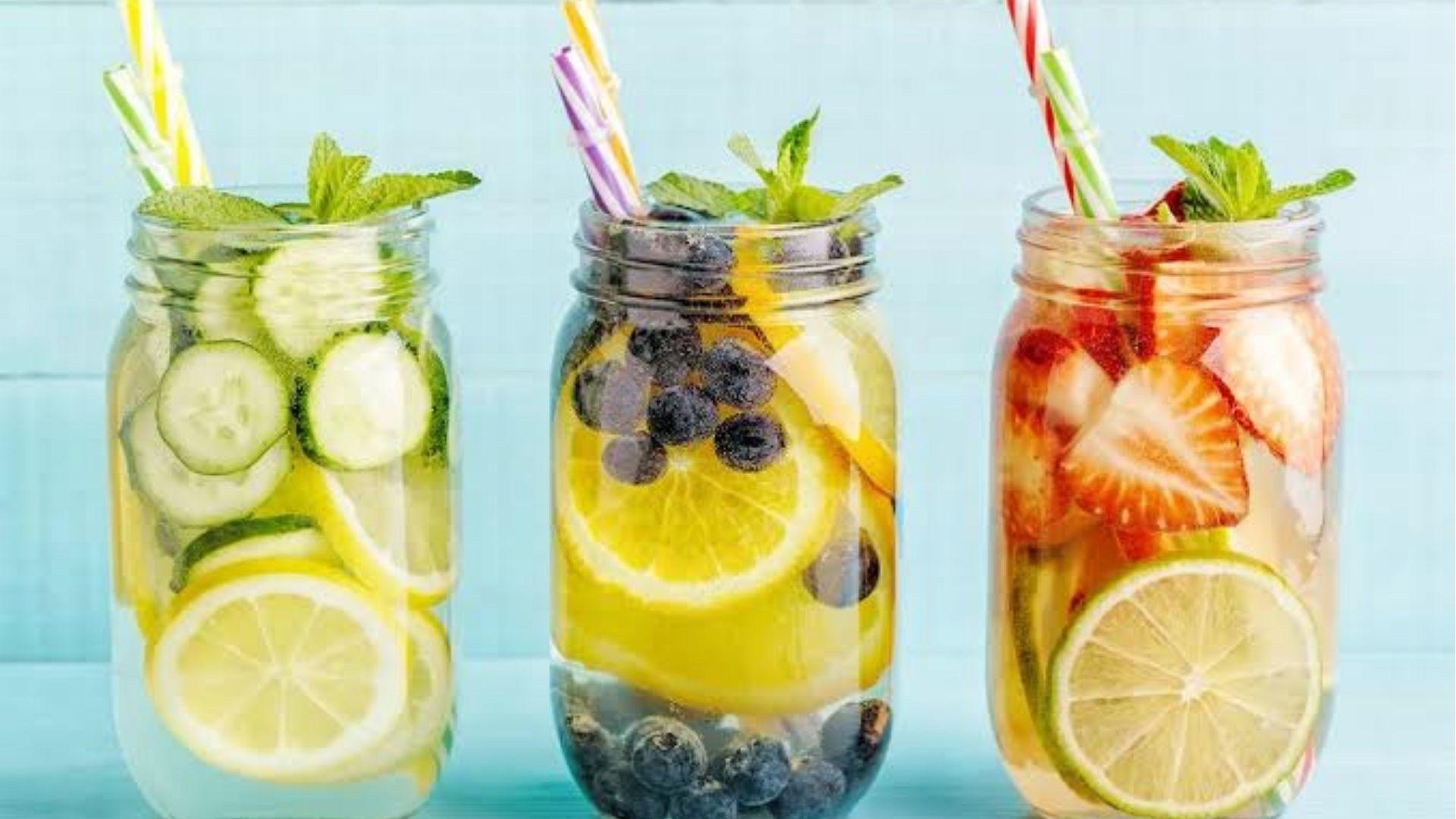 Three jars with infused fruit water cucumber lemon blueberry strawberry mint detox drinks.