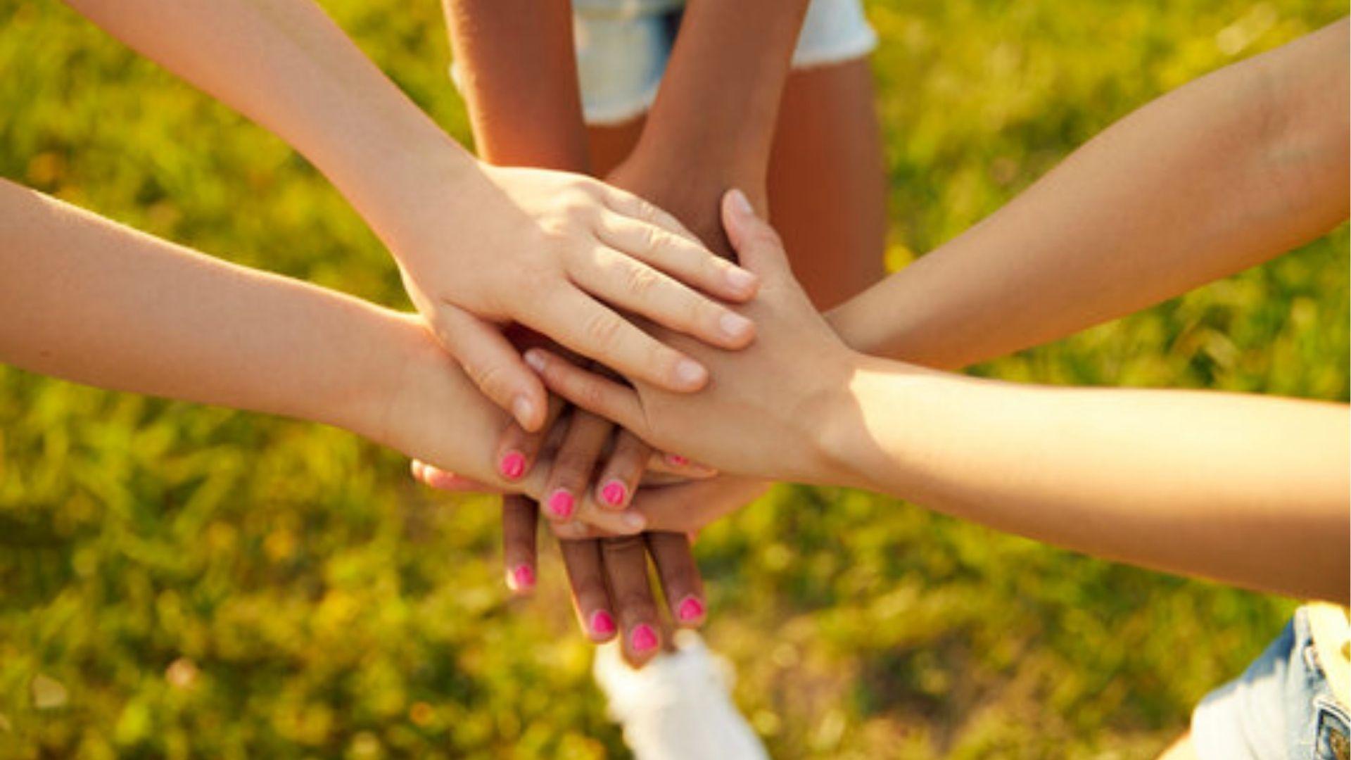 Several hands stacked in a pile.