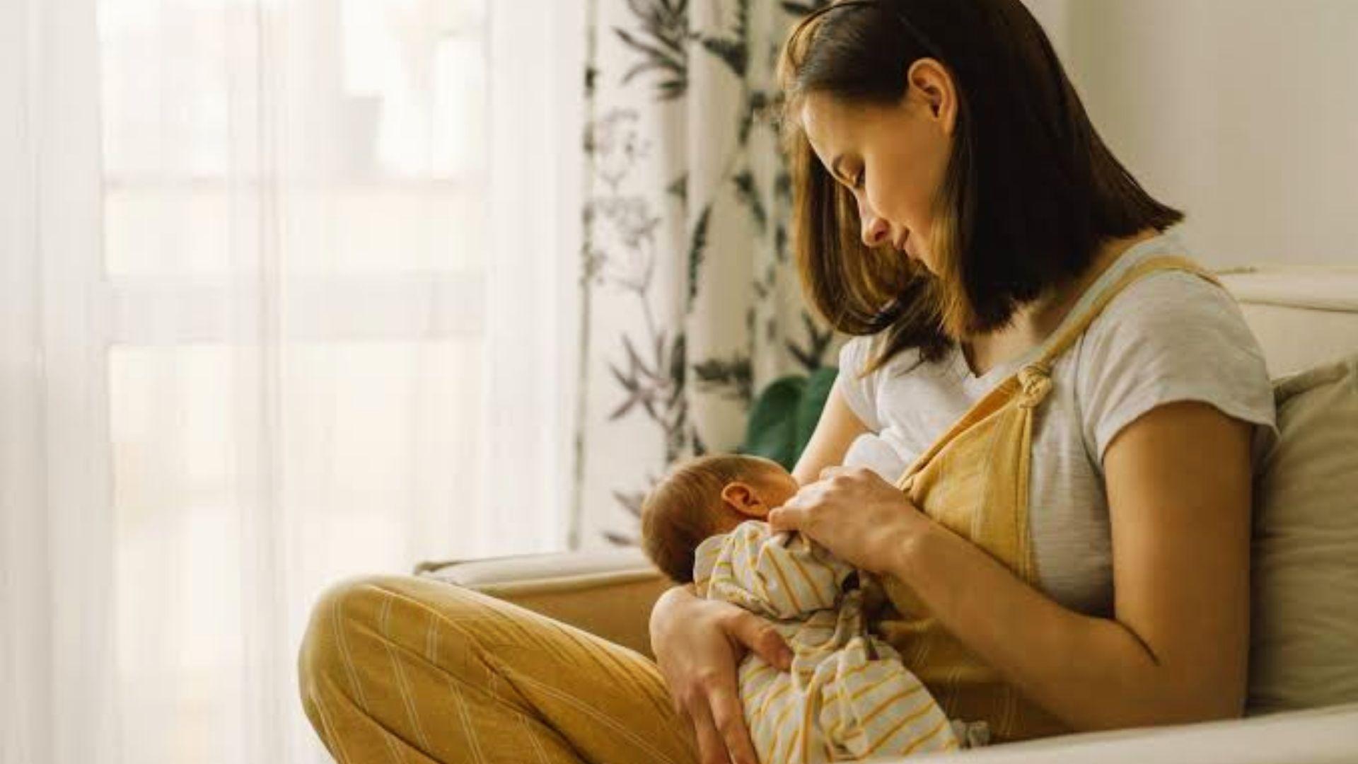 Mother breastfeeding newborn on couch.