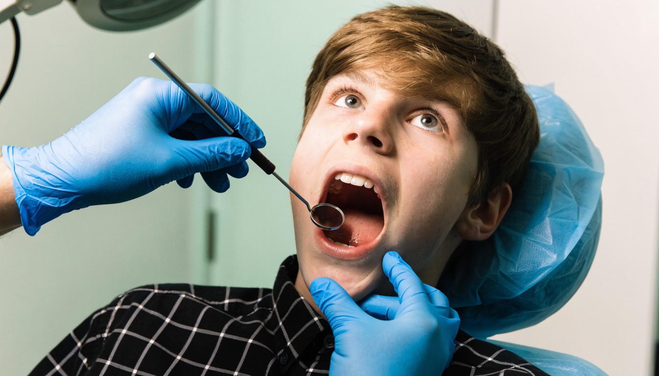 A white American boy child with mouth open in the dental clinic showing up for the checkup
