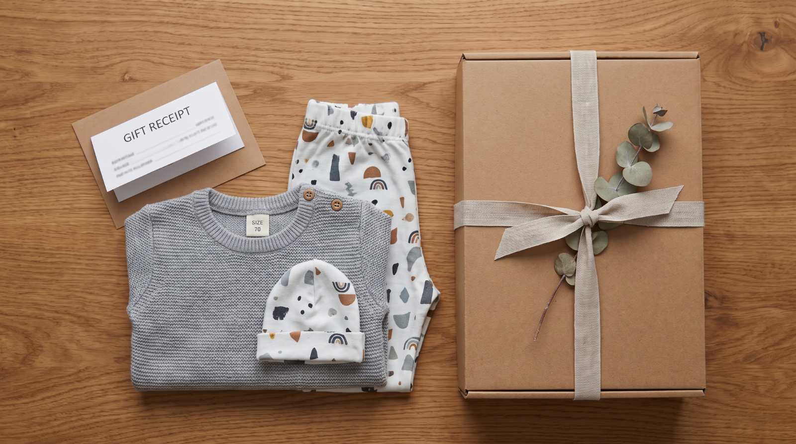 Folded baby clothes arranged with gift packaging and a gift receipt