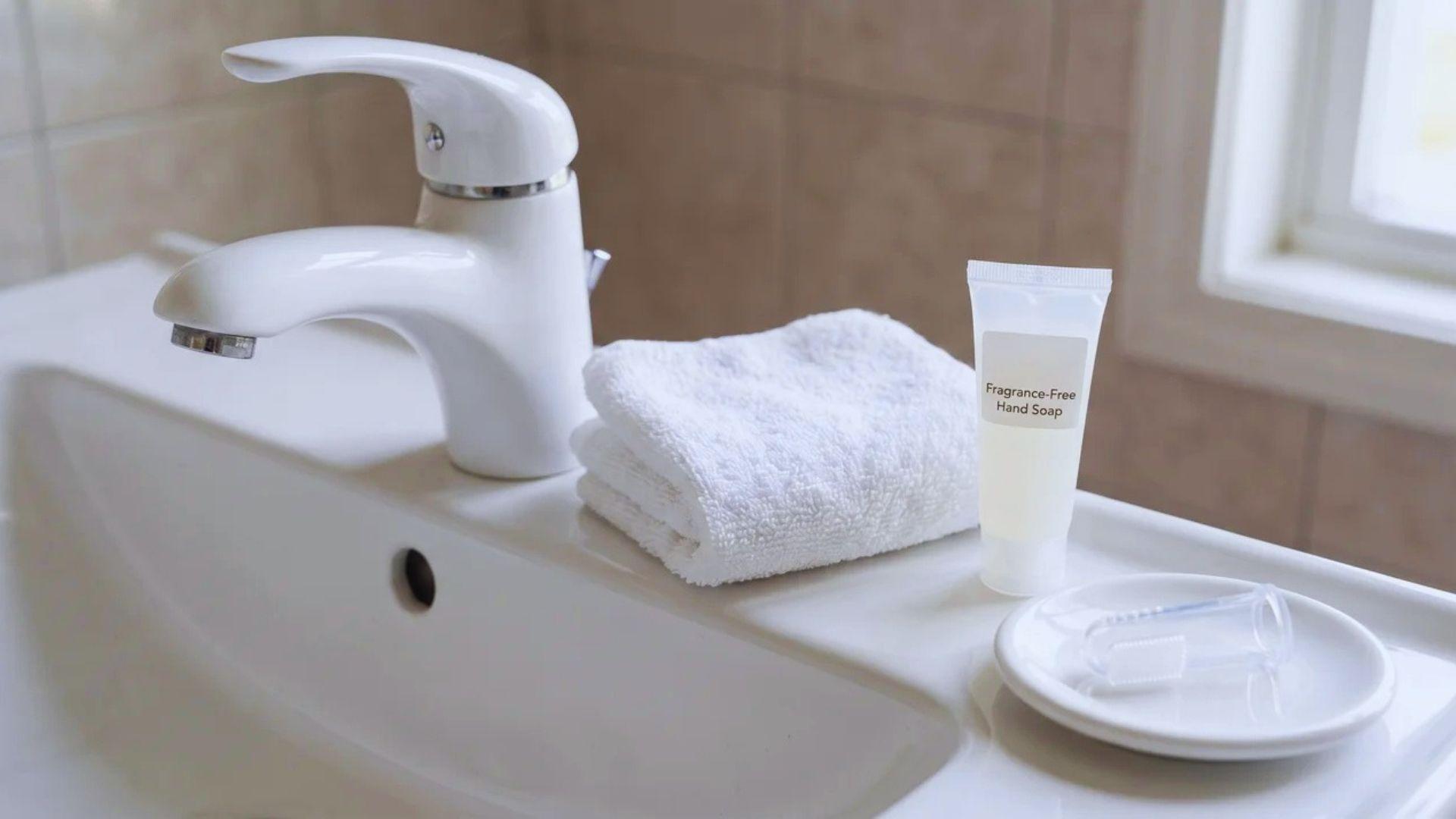 Clean finger toothbrush and handwashing supplies arranged beside a bathroom sink.