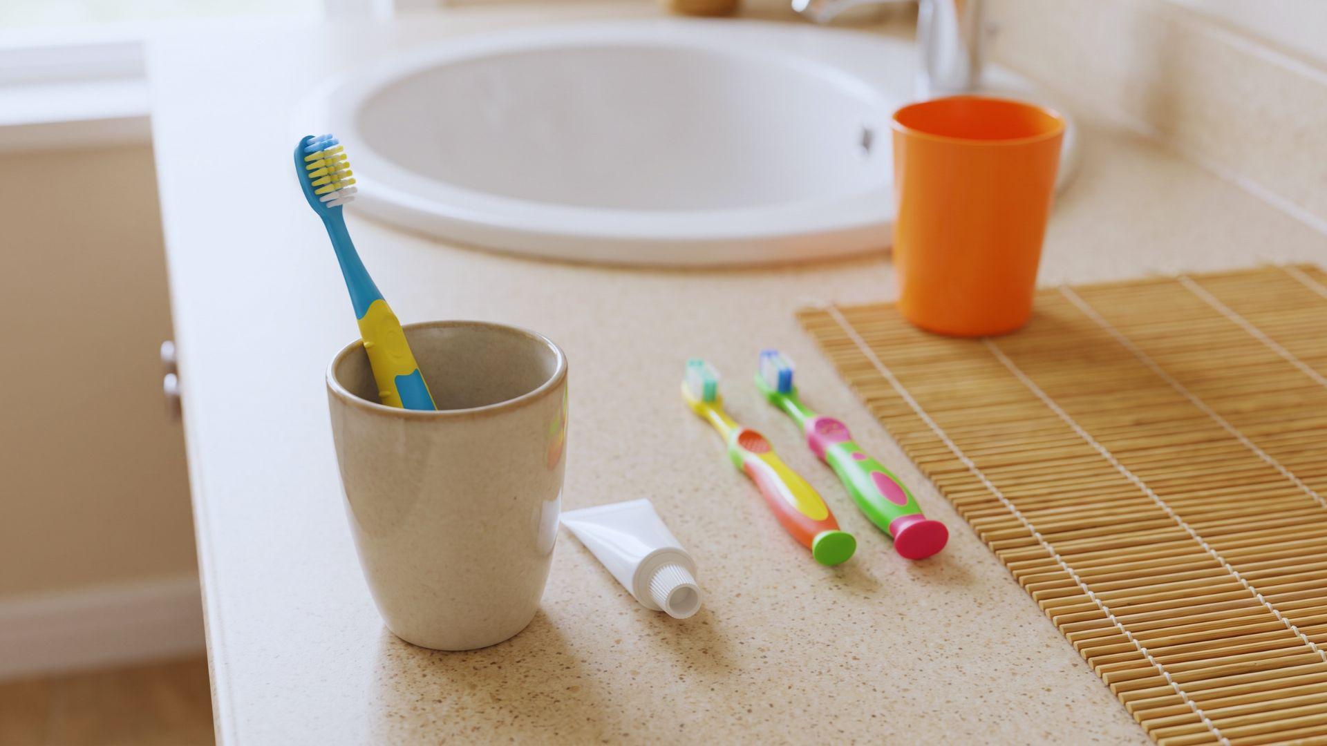 Children's toothbrushes and fluoride toothpaste arranged beside a bathroom sink.