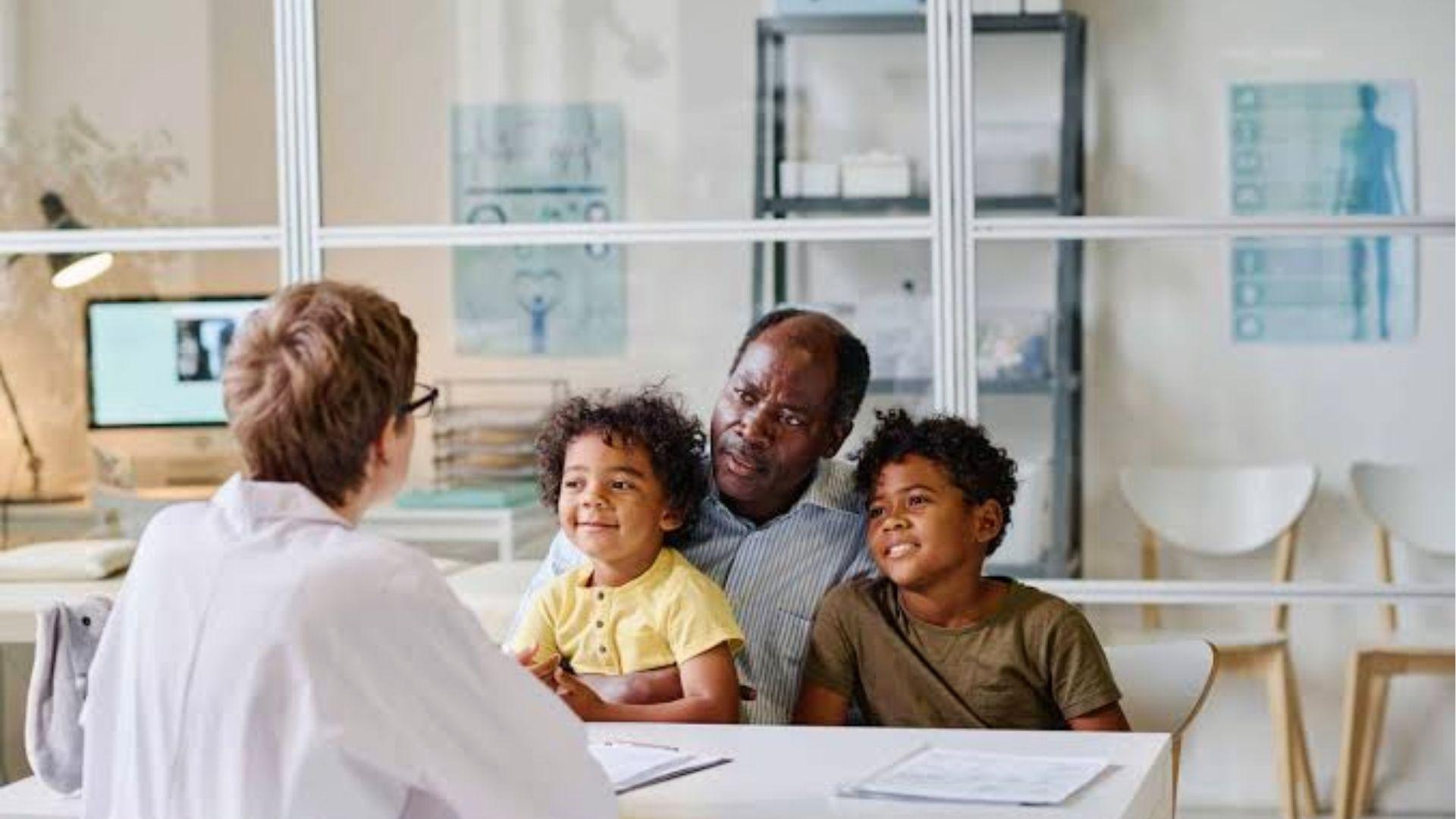 Father with two kids discussing braces for children with dentist in modern clinic office.